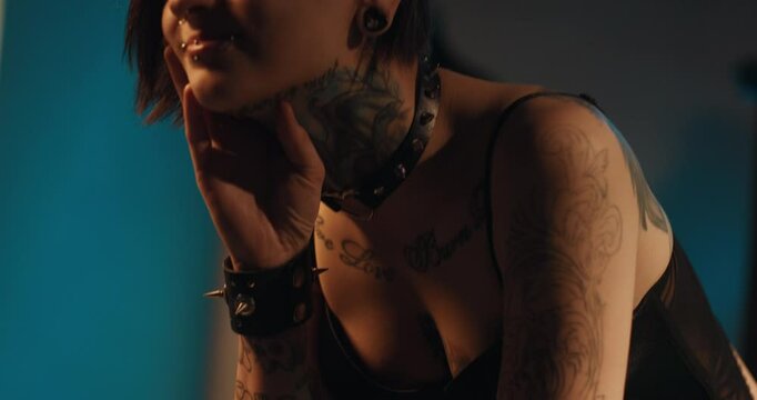 Individuality, and self-expression by tattoos and piercing, stay yourself. Young woman in informal clothes and patterns on body in dark room, seduction and temptation, sensual female sexuality