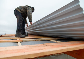A man is working on a roof, painting it
