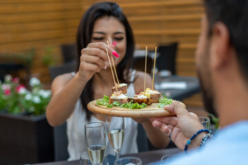 Close-up of a woman picking food from a shared platter during elegant outdoor gathering
