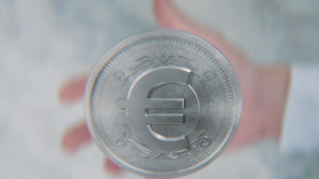 A hand flips a coin marked Dollar and Euro, spinning toward the camera in slow motion