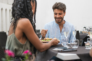 Man smiling while sharing food during an elegant outdoor dinner