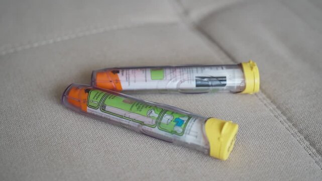 Two Epinephrine autoinjectors on a couch 2
