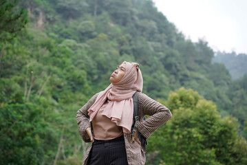 Young Indonesian female traveler wearing hijab looking exhausted while traveling in nature, travel concept.