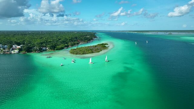 Drone circles around boats sailing on emerald green lagoon under blue sky, Lagoon of seven colors, Bacalar, Quintana Roo