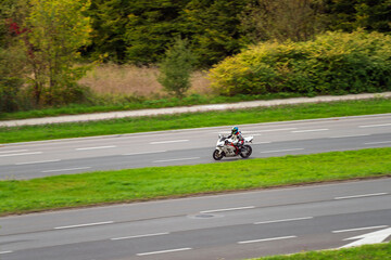 Motorcyclist in helmet riding suburban highway