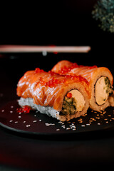 Sushi on a board on a black background. Philadelphia set. Rolls in smoke. Japanese cuisine concept