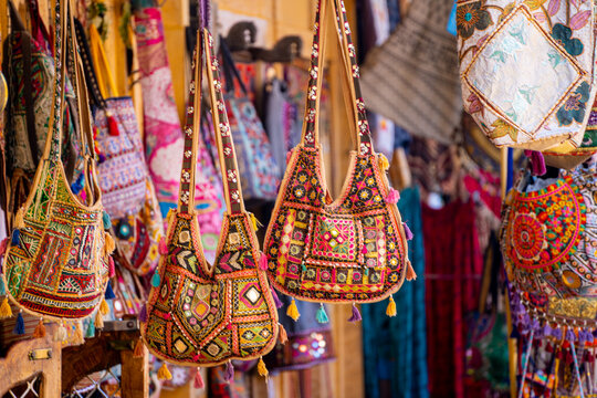 Colorful handmade traditional rajasthani bags with mirrors, embroidery, tassels hanging outside a street vendor shop ready for sale to tourists