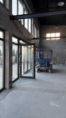 Naklejka premium Close-Up and Interior Views of a Blue Industrial Lift in a Spacious, Raw Concrete Warehouse
