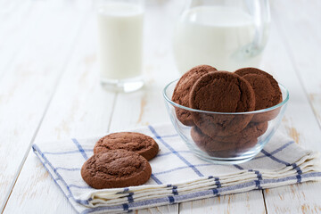 Chocolate brownie cookies and a jug of fresh milk on a light kitchen table, healthy breakfast.