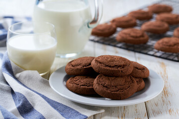 Chocolate brownie cookies and a jug of fresh milk on a light kitchen table, healthy breakfast.
