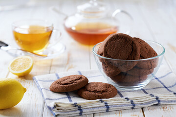 Chocolate brownie cookies and tea on a white table, close up.