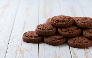 Heap of chocolate brownie cookies on a white table, with copy space for text.
