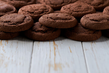 Heap of tasty chocolate cookies on a light kitchen table, selective focus.