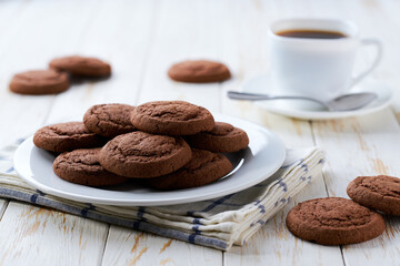 Delicious chocolate brownie cookies and coffee on a light kitchen table, selective focus.