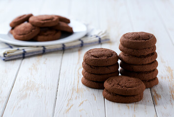 Tasty chocolate cookies in a plate with on a light kitchen table, selective focus.