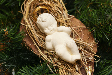 Small figurine of baby Jesus on hay with a halo aureole. Christmas decoration for the holiday...