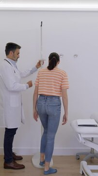 Medical professional assesses patient's height and weight using specialized equipment in a clinical setting