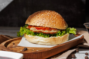 hamburger with green salad, tartar sauce, ketchup, sesame bun, on a dark background with sauces, fast food, snack
