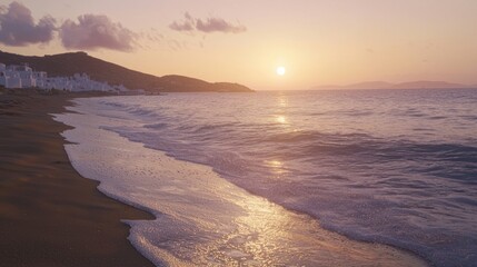 Obraz premium Sunrise over calm ocean waves on sandy beach with white buildings in background.