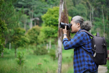 male professional photographer taking photos of natural scenery while walking in the forest, travel concept.