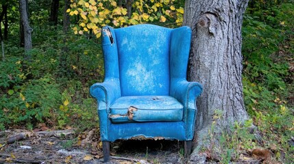 Old Worn Blue Armchair Next to Tree in Forested Area