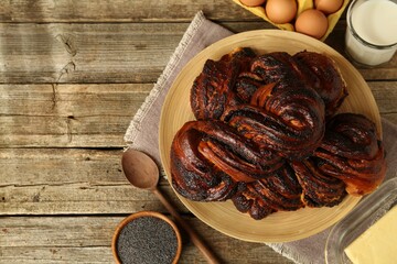 Tasty buns with poppy seeds and ingredients on wooden table, flat lay. Space for text
