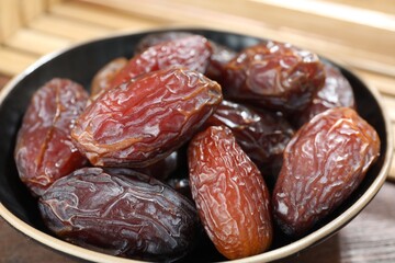 Many tasty dried dates in bowl on table, closeup