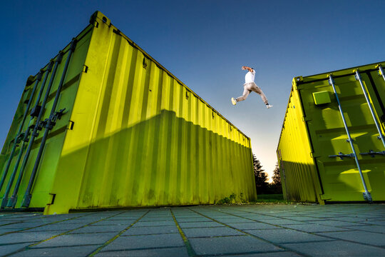 Man jumping over green containers