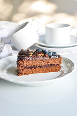 chocolate sacher cake decorated for party. neutral white background with kitchen elements. homemade chocolate cake.
