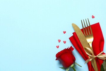 Valentine's Day concept. Top view photo with cutlery, red rose and confetti on color background with empty space