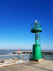 Lighthouse on the pier against the blue sky and the sea.