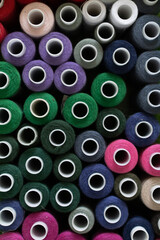 A large group of various colorful spools of thread for sewing at the workplace in a small business studio. view from above