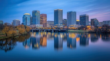 Fototapeta premium City skyline reflecting in calm water at dawn.