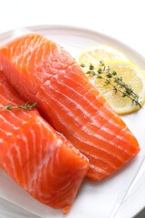 Pieces of fresh salmon with thyme and lemon on white table, above view