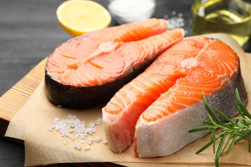 Fresh raw salmon steaks and spices on black table, closeup