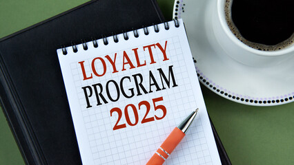 LOYALTY PROGRAM 2025 - words in notebook on green background with cup of coffee