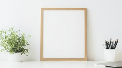 Blank frame mockup on white desk with plant and pencils.