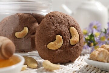 Tasty chocolate cookies with cashew on wicker mat, closeup