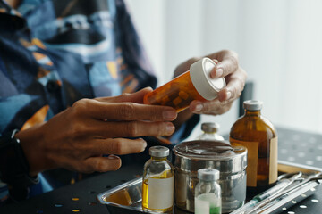 Medium closeup of hands of unrecognizable woman checking expiration date of medications in jar