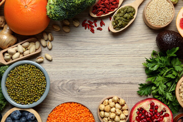 Frame of different superfood products on wooden table, flat lay. Space for text