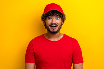 Young man in a red shirt and hat surprised against bright yellow background