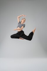 Girl performing an expressive dance leap in a minimalist studio setting