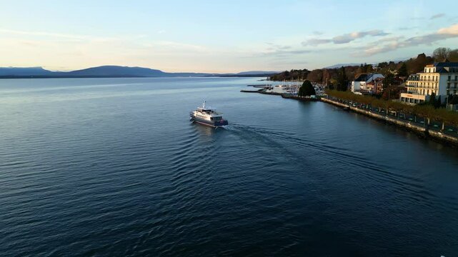 Orbit drone shot of boat sailing on Lake Geneva at sunrise in Nyon Switzerland
