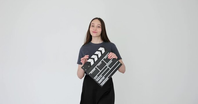 Young woman holding clapperboard in studio against white background