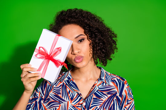 Photo portrait of pretty young girl hold pesent box kissing wear trendy colorful outfit isolated on green color background