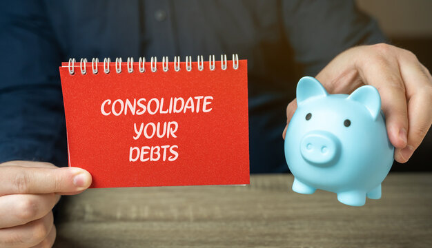 Consolidate your debts concept. Combining multiple debts, such as credit card balances, personal loans, or other liabilities, into a single loan or payment plan. A notebook, piggy bank in the hands
