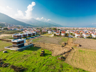 Panoramic shot of a residential neighborhood with mountains in the background and bulldozer near a...
