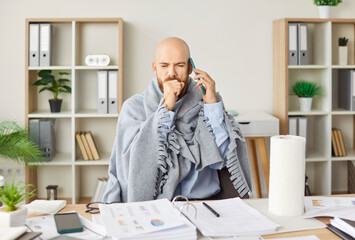 Sick man sitting at desk coughing working, phone call, blowing running nose, suffer from flu or cold at home, ill male worker feels unhealthy struggle with influenza under blanket, employee healthcare