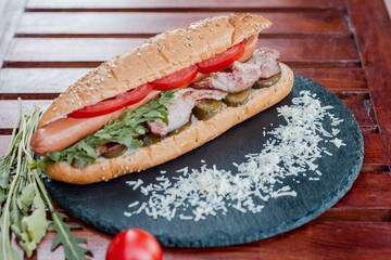 hot dog with sausage, tomato and pickled cucumber