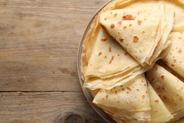 Delicious folded crepes on wooden table, closeup. Space for text